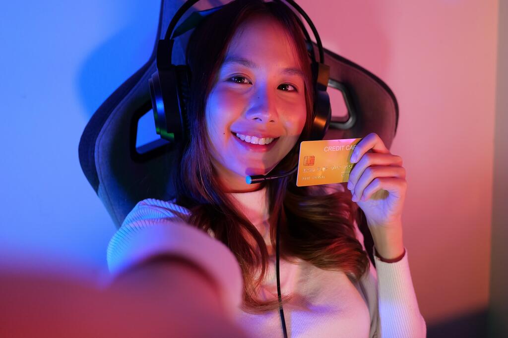 Female gamer make purchase within game, Gamer holding credit card